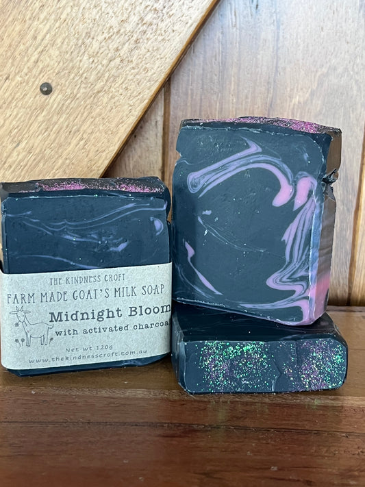 Three bars of slack and pink swirled soap with a label on a wooden surface