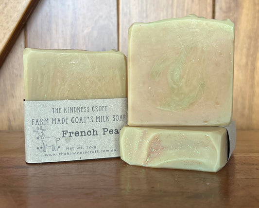 Three bars of soap on a wooden surface with one bar showing a label.