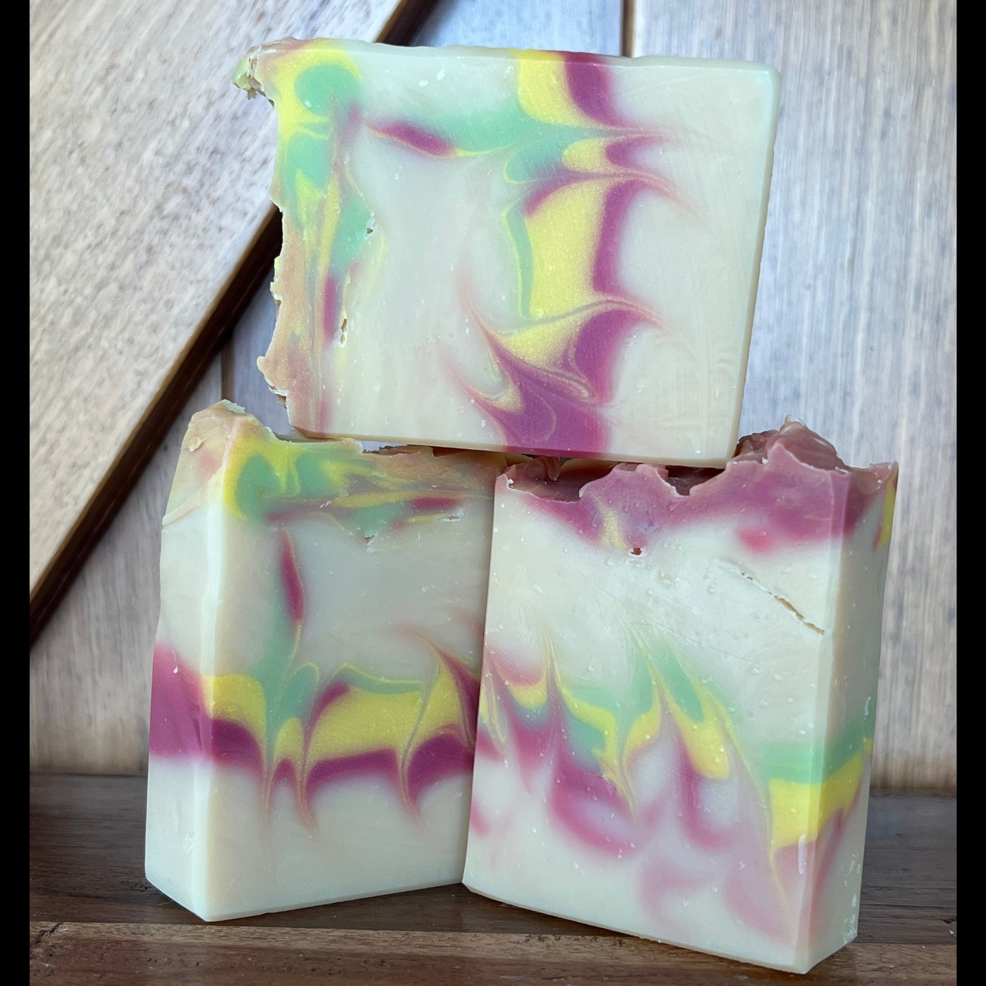 Three bars of colorful soap with a marbled pattern on a wooden surface.