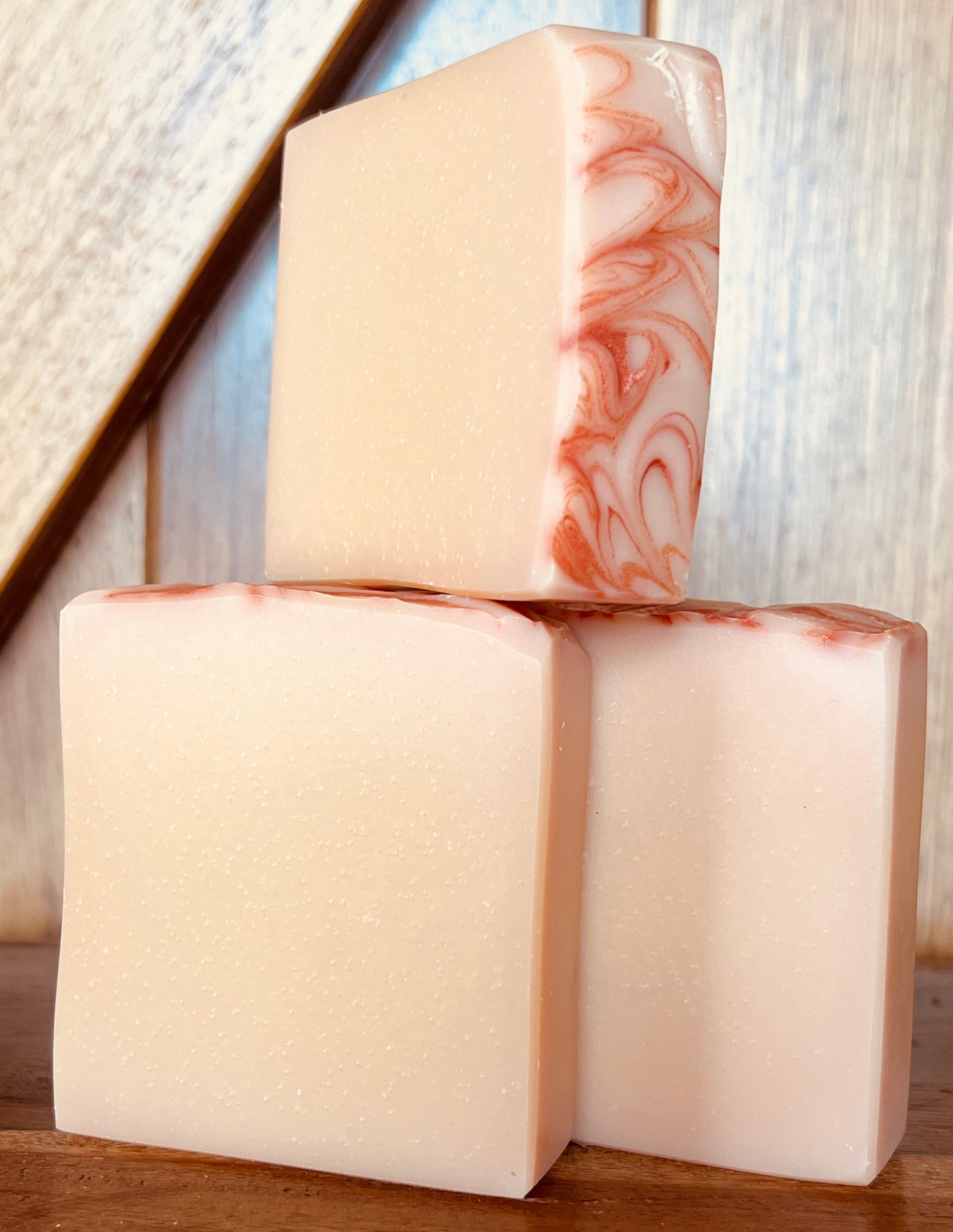 Three bars of soap with marbled patterns on a wooden surface