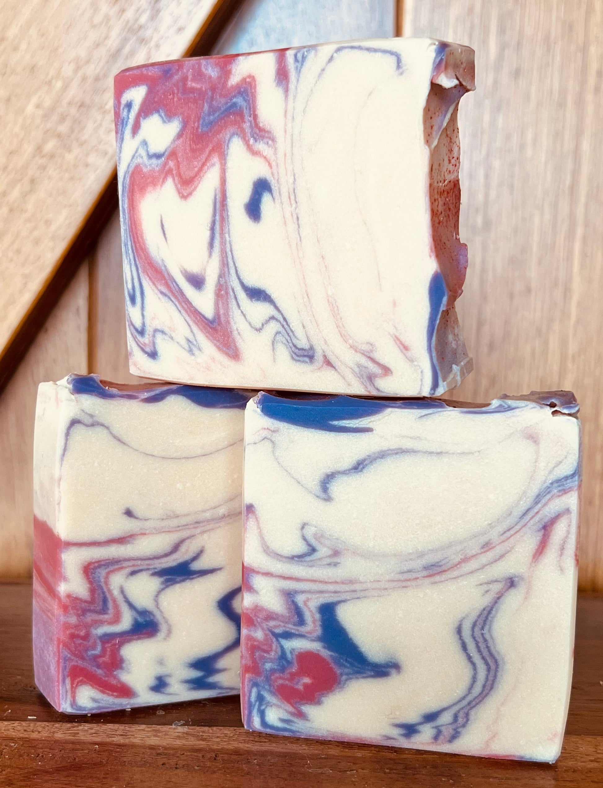 Three bars of marbled soap on a wooden surface