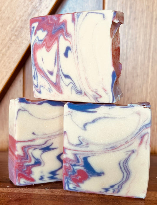 Three bars of marbled soap on a wooden surface